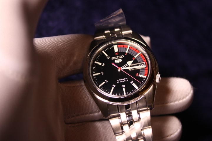 Seiko 5 SNK375K1 de frente, esfera negra con detalles rojos